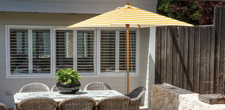 Yellow market umbrella with bamboo-look pole shading an outdoor setting